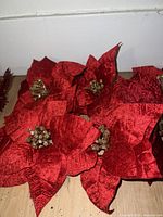 Close-up photo showing a cluster of multiple red silk artificial flowers with textured petals and gold-tone stamen centers.
