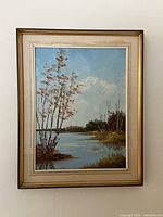 Full frontal photo of the framed signed landscape oil painting depicting a water scene with trees and sky.