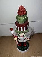 Front view of the small leprechaun nutcracker figurine showing glittered hat, white fur collar, and candy cane staff.