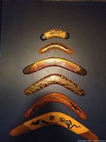Full set of six wooden Indigenous Australian boomerangs with various painted traditional patterns and designs