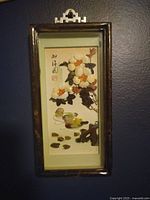 Photo of the vertical Chinese shadow box featuring floral design with abalone shell and mother of pearl inlay in a wooden frame.