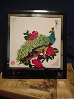 Frontal view of the Chinese shadow play box showing a colorful peacock and floral design inside a black frame