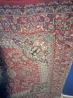 Close-up of the red and beige floral patterned area of the Eaton polypropylene rug, showing intricate traditional design.