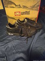 Pair of black Echo unltld. sneakers with branded box behind