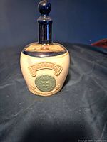 Front view of ceramic Kings Ransom empty scotch bottle on black surface.