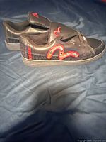 Side view of the black Evisu sneaker showing detailed logo design on the side and condition of upper material and sole.