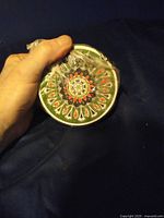 Top view of one coaster showing intricate painted traditional Greek-style pattern in multiple colors.