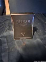 Front view of sealed box featuring Guess Seductive Homme brand and logo, showing dark packaging with silver text.