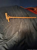 Full length photo showing natural bark wooden pipe on dark fabric background.