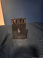 Black rectangular box with gold lettering and logo of polo player on horse. Front view showing brand and product details.