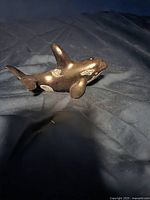 Front and side views of a small soapstone whale sculpture on a dark fabric background.