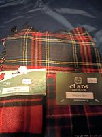 Three wool scarfs laid out showing tartan patterns and attached labels