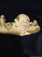 Front view of the soapstone carving showing human and animal figures and an igloo.