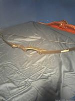 Full view of the youth bow laid flat, black finish with curved grip area and string attached.