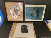 Full view of three items: two framed First Nations prints and one unframed black and white portrait print on rice paper placed on cardboard.