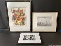 Three framed art prints arranged on table: abstract geometric, seascape, lino cut