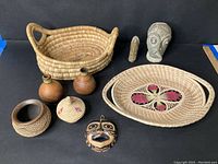 Photo showing full lot including baskets, bottles, mask, and carved figures arranged on black background
