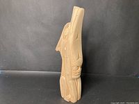 Side view of tall wooden sculpture carved in traditional First Nations style.