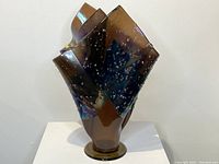Front view of the large art glass vase showing its abstract, wave-like edges and iridescent coloration with bubbles throughout the glass.