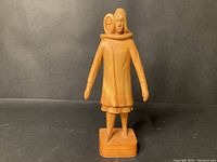 Front view of the wood carving showing the mother holding the child over shoulder.