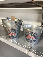 Stack of nine metal Coors Light ice buckets on a shelf