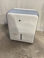 Front and side view of white Vremi dehumidifier showing brand logo and moisture window.