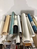 Collection of rolled paper posters and prints laid out on table