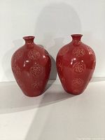 Front view showing pair of large red ceramic vases with raised floral patterns
