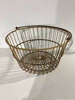 Front side angled view of the large vintage wire basket showing rounded shape, metal rods, and patina.