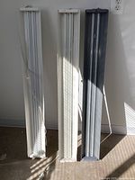 Front view of the three LED shoplights standing vertically side by side, two with white casings and one gray.