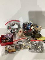 Full lot showing bags of pins, patches, a small white toy figure, tins, and souvenir spoons.