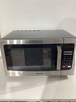 Front view of the Toshiba microwave showing stainless steel finish and glass door with Toshiba branding.