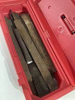 View of five vintage metal files placed inside a red Craftsman plastic box. Files show wear and rust.