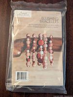 Front of unopened DIY kit showing bracelet designs with pink and wood beads on display.