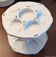 Side view showing two stacked circular tiers with designed indentations for holding cans securely.