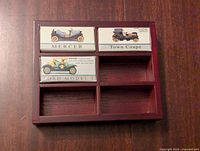 Top view of wooden display case with three boxed model cars: Mercer, Town Coupé, Ford Model T, showing arrangement.