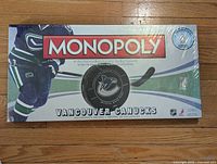 Front of sealed Vancouver Canucks Monopoly collector's edition board game showing team colors, a hockey player image, and the logo.
