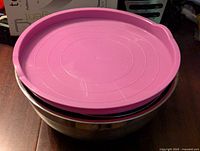 Photo showing stack of large stainless steel mixing bowl with purple lid on top.