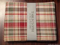 Front view of new plaid tablecloth with multicolor pattern folded and in packaging.