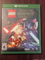Front cover of Xbox One LEGO Star Wars The Force Awakens game case showing LEGO characters with lightsabers and branding.