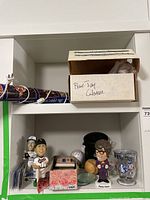 Shelf view of bobbleheads including Cal Ripken and Pat Borders, signed baseballs, a display box marked 'Blue Jay Glasses', and assorted cards and pins.