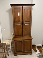 Front view of the wooden cabinet showing two upper doors and two lower doors with metal handles.