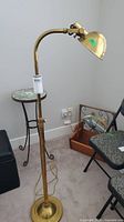Full view of the brass floor lamp showing the base and adjustable neck.
