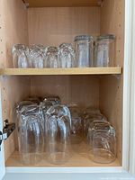 Overview of the glasses arranged in a wooden cabinet shelf showing multiple sizes and quantities.