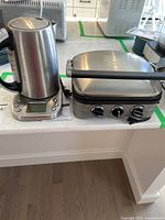 Photo showing the Hamilton Beach electric kettle and Cuisinart electric griddle side by side on white counter.
