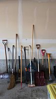 Full view of the entire lot showing all tools lined up against the wall on a concrete floor.