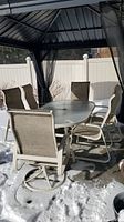Full set of oval table and six chairs under gazebo, shown from front left angle.