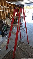 Full view of the 6-foot red step ladder standing in a garage, showing its structure and condition.