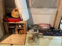 Shelf with assorted household hardware including door knobs, cables, small tools, socket set case, and professional file set.