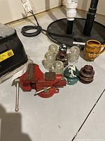 Red metal 3.5 inch swiveling vice with handle, showing wear and use marks, placed on a flat surface